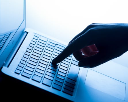 a hand presses a button a darkened laptop keyboard