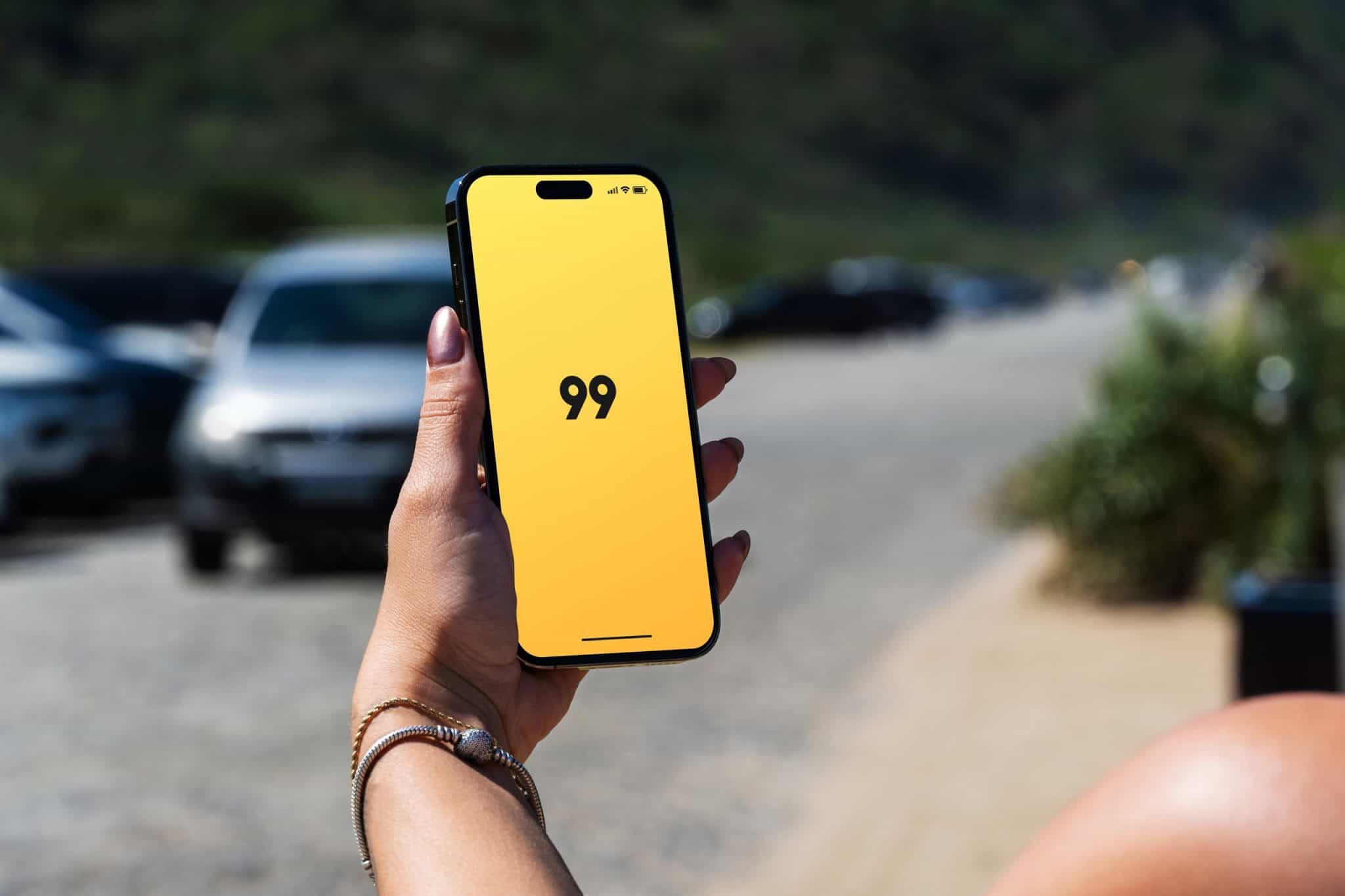 Logo da 99 em um smartphone na mão de uma pessoa